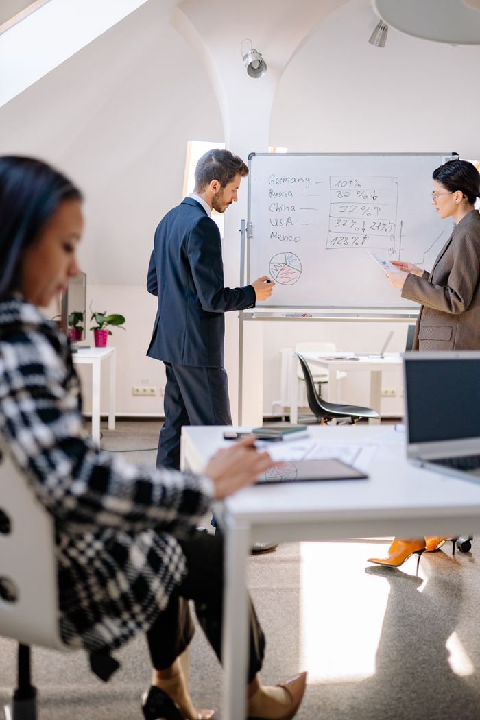 Business professionals collaborating on data analysis with a whiteboard in a modern office setting.