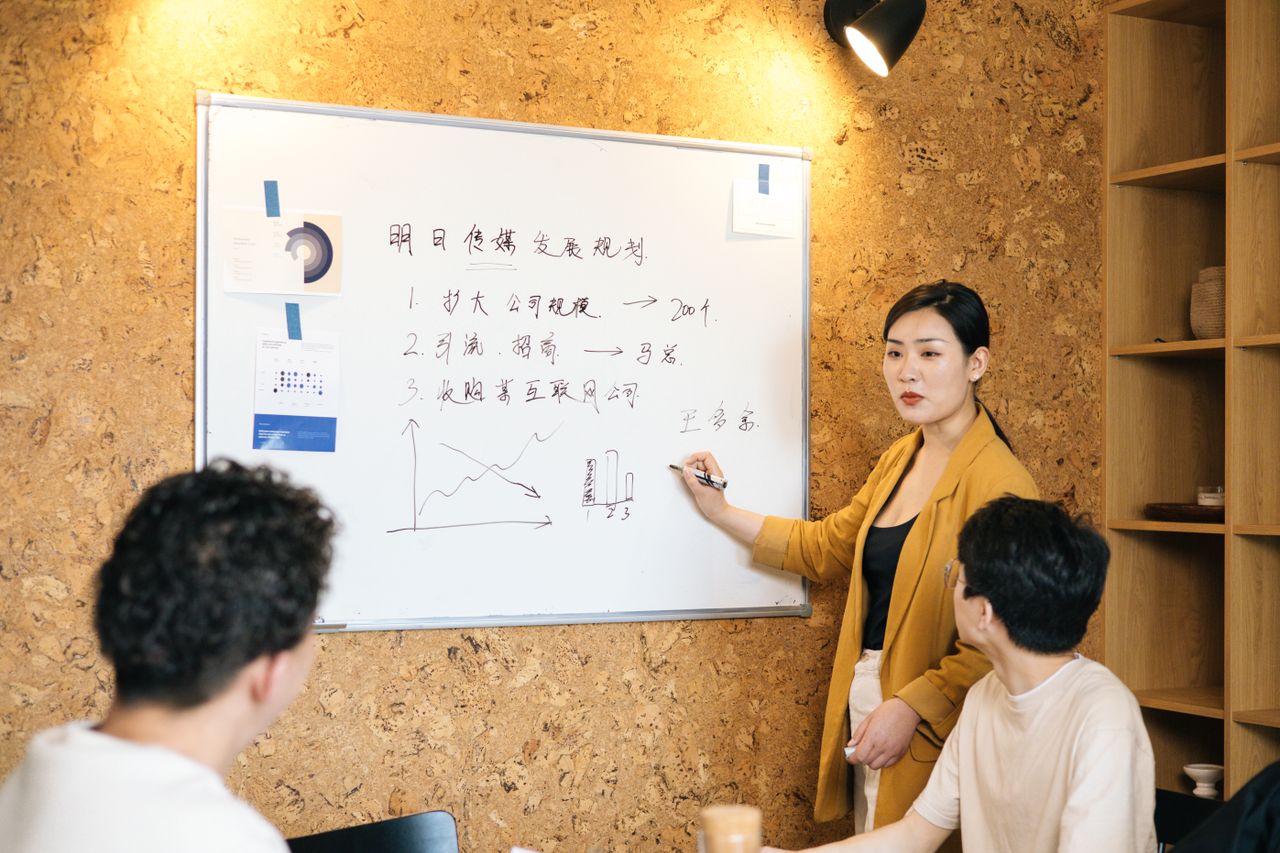 Business team brainstorms strategies on a whiteboard during a meeting.
